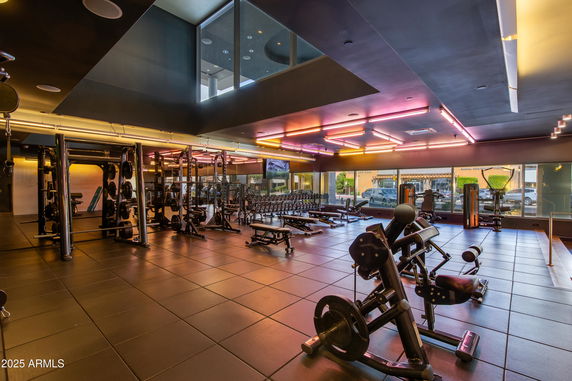 Interior view of a gym area with exercise equipment and neon lighting.