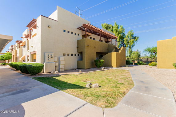 Front view of a two-story building with a unique staircase and pergola structure.