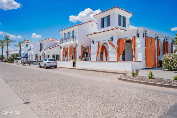 Front view of a two-story building with white facade and orange curtains.