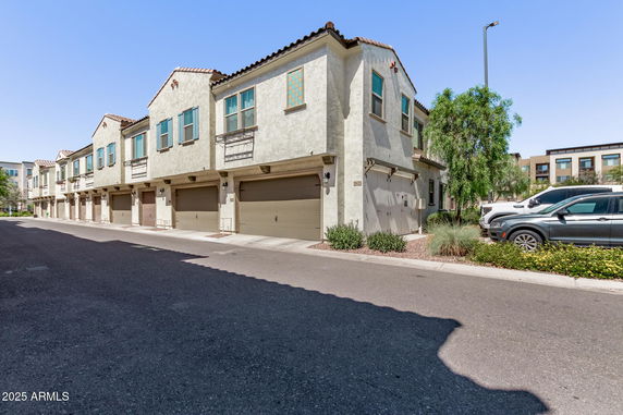 Front view of a row of townhouses with garages on the ground level.