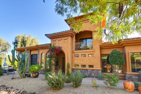 Front view of a two-story house with arched doorway and balcony.