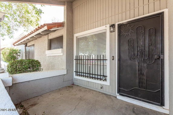 Front view of a house entrance with a decorative metal door and window with bars.