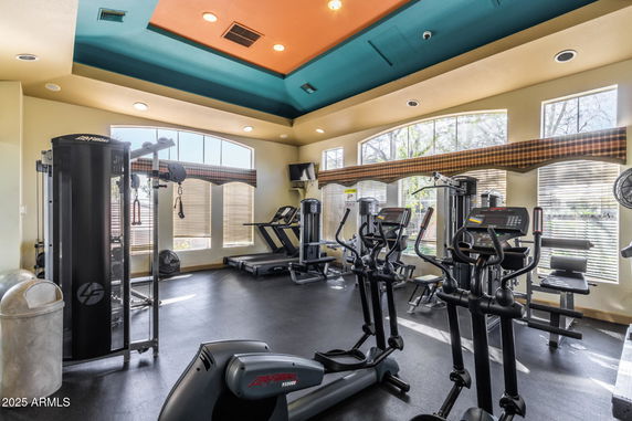 Interior view of a gym with various exercise equipment and colorful ceiling.