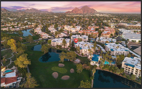 Wide aerial view of residential buildings and surrounding landscape with mountains in the background.