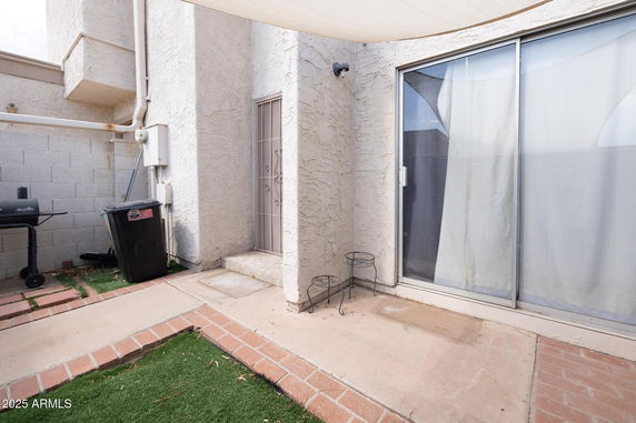 Side view of a house with a sliding door and a small patio area.