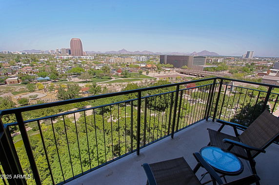 Balcony view overlooking cityscape with buildings and mountains in the distance.