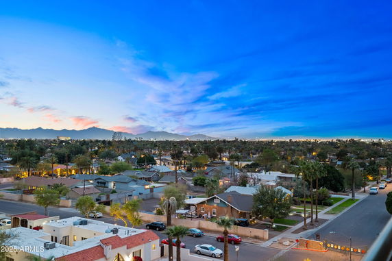 Wide angle view of a residential neighborhood with houses and a distant mountain range under a blue sky.