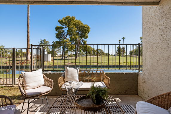 Outdoor seating area with a view of grass, water, and trees.