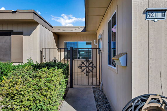 Front view of a house with a gated entrance and wooden exterior.