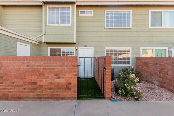 Front view of a two-story house with a brick fence and gated entrance.