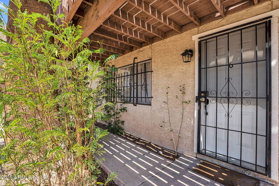 Front view of a house entrance with a gated door and window, covered by a wooden lattice.