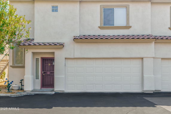 Front view of a two-story house with a garage and a red entry door.
