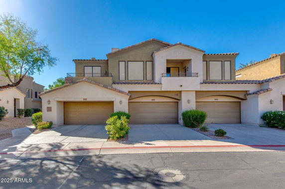 Front view of a two-story house with multiple garages and a balcony.