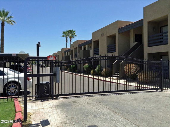 Front view of a multi-story apartment complex with a gated entrance.