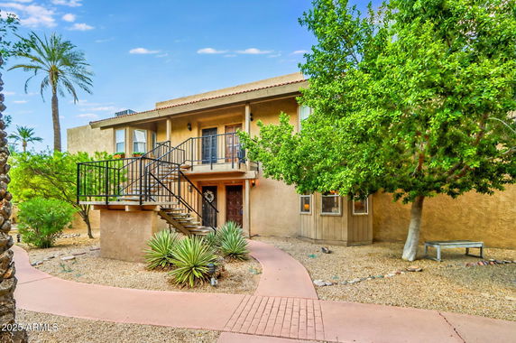 Front view of a two-story house with an exterior staircase and balcony.