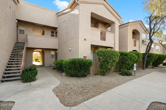 Front view of a two-story apartment building with balconies and exterior stairs.