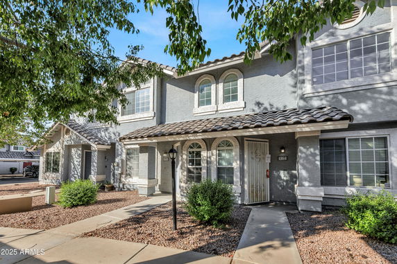 Front view of a two-story house with arched windows and a tiled roof.