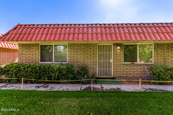 Front view of a single-story house with a red tile roof and brick exterior.