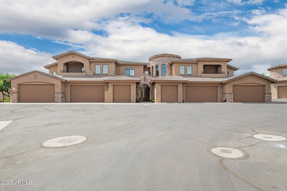 Front view of a multi-story building with multiple garage doors and a central stone tower.