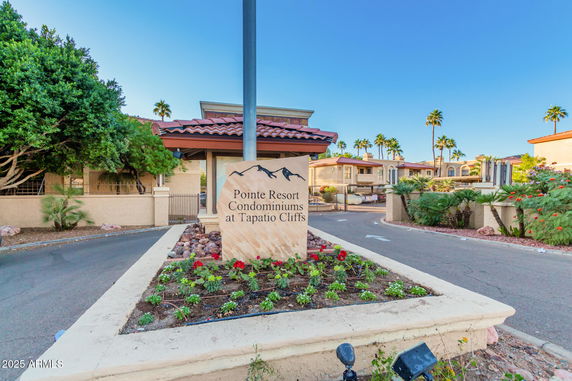 Front view of a condominium complex entrance with signage and landscaped area.