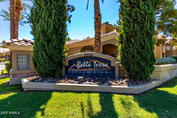 Front view of a condominium building with a sign reading 'Bella Terra at Paradise Valley Condominiums' and landscaping.