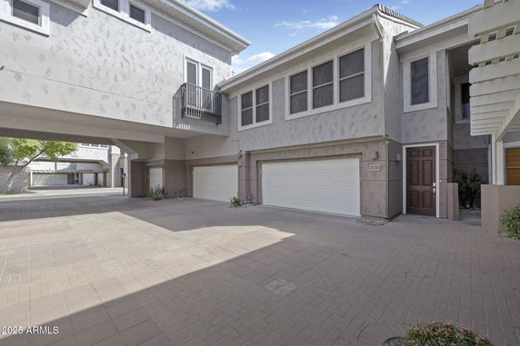 Front view of a two-story building with garages and balcony.