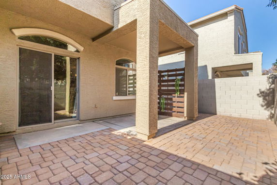 Side view of a two-story house with a patio and sliding glass door.