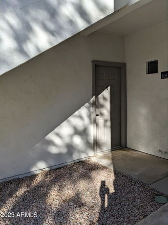 Exterior view of a building corner with a door and concrete pathway.