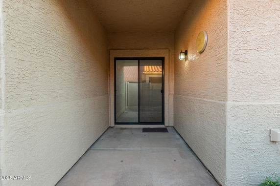 Entrance of a house with sliding glass doors and wall light fixture.