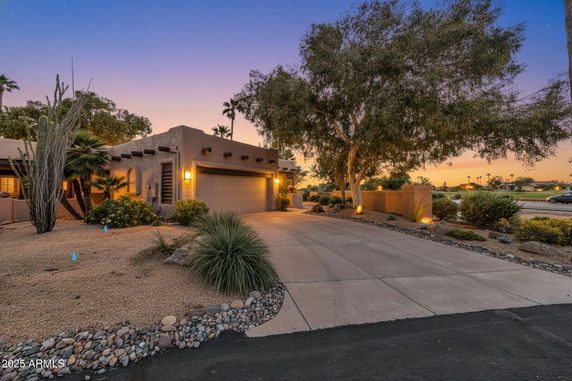 Front view of a single-story house with desert landscaping and a two-car garage.