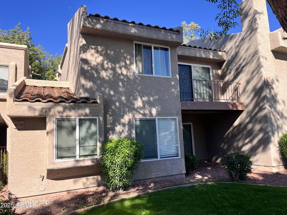 Front view of a two-story house with a balcony and tiled roof.