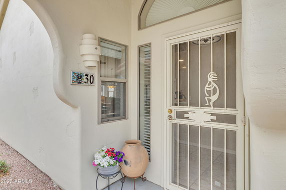 Front view of a house entrance with a decorative metal screen door and a small window.