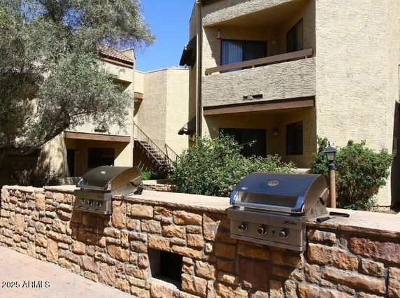 Front view of a multi-story building with balconies and outdoor grills.