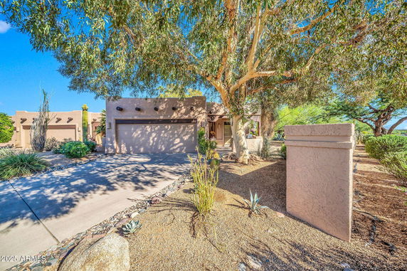 Front view of a house with a double garage and desert landscaping.
