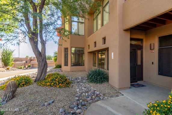 Front view of a house with multiple large windows and a gravel landscaping.