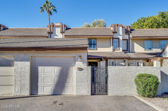 Front view of a multi-story house with a garage and a small gated entrance.