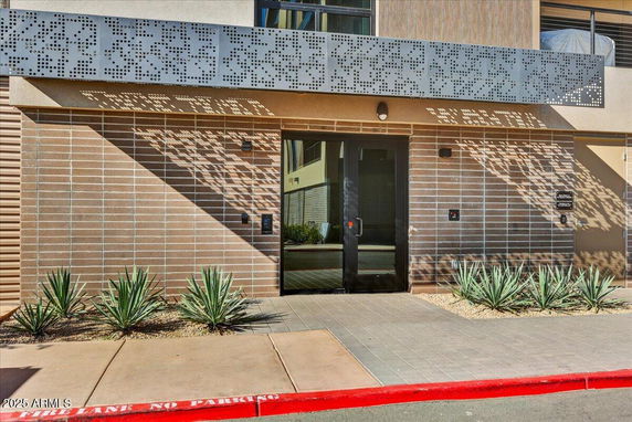 Front view of a building entrance with a modern facade and decorative perforated metal panel.