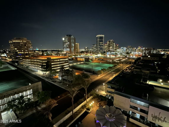 Nighttime panoramic view of a city skyline with illuminated buildings and streets.