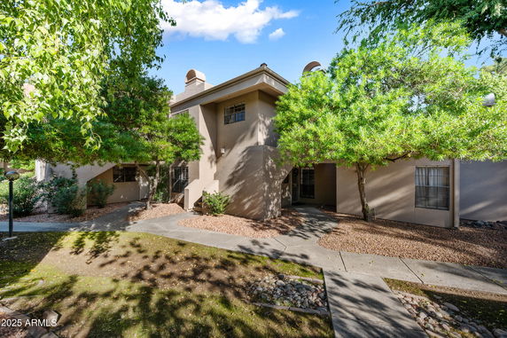 Front view of a two-story house with beige exterior and surrounding trees.