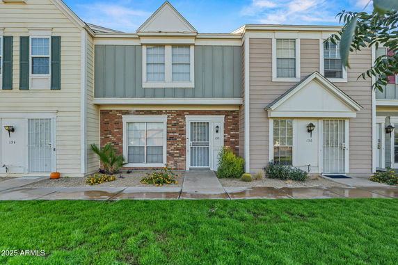 Front view of a two-story townhouse with a mix of brick and siding exterior.