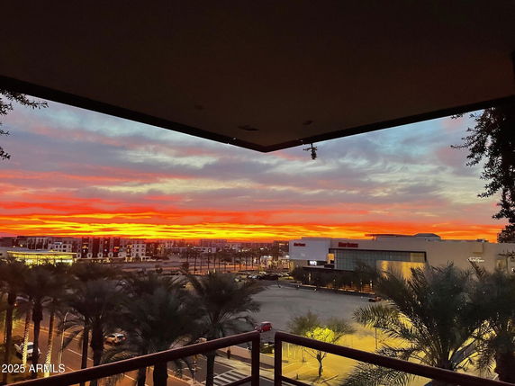 Panoramic view from a building with a colorful sunset and cityscape in the background.
