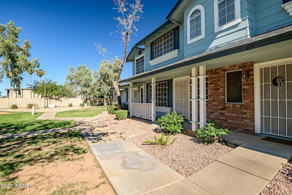 Front view of a two-story townhouse with a porch and brick accents.