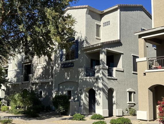 Front view of a two-story house with balconies and arched entrances.