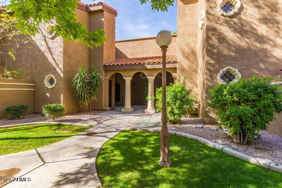 Front view of a building with stucco walls and decorative windows.