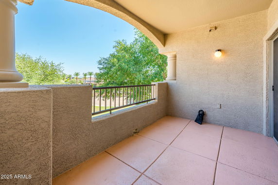 View from a balcony area featuring trees and palm trees in the background.