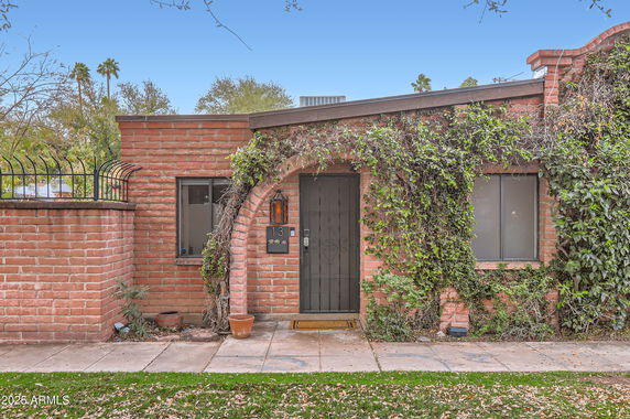 Front view of a single-story brick house with ivy on the facade.