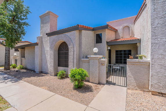 Front view of a single-story house with arched windows and a gated entrance.