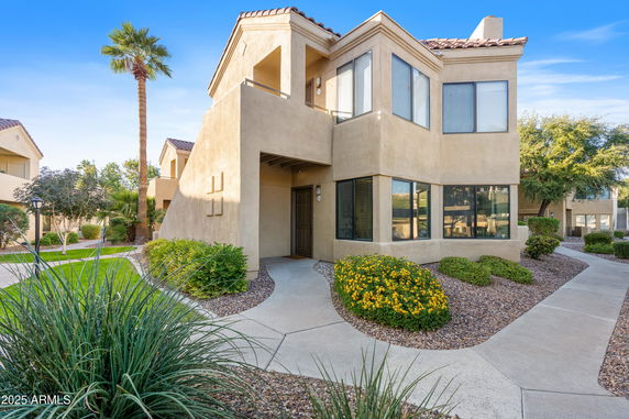 Front view of a two-story house with beige exterior and large windows.