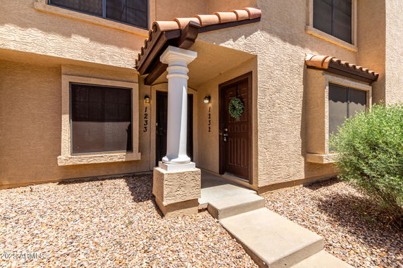 Front view of a multi-story house entrance with stucco exterior and decorative column.