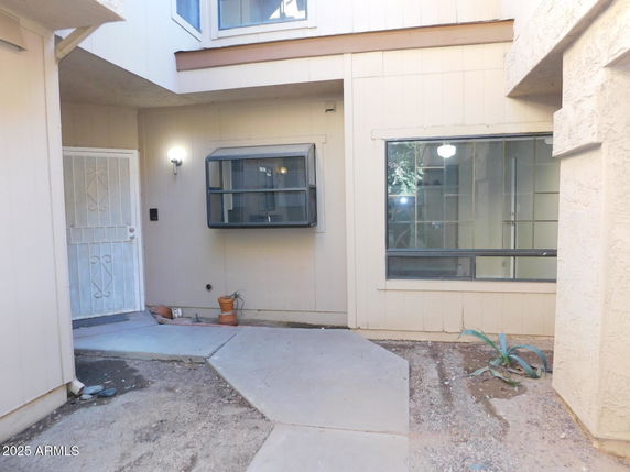 Front view of a house entrance with metal gate and windows.